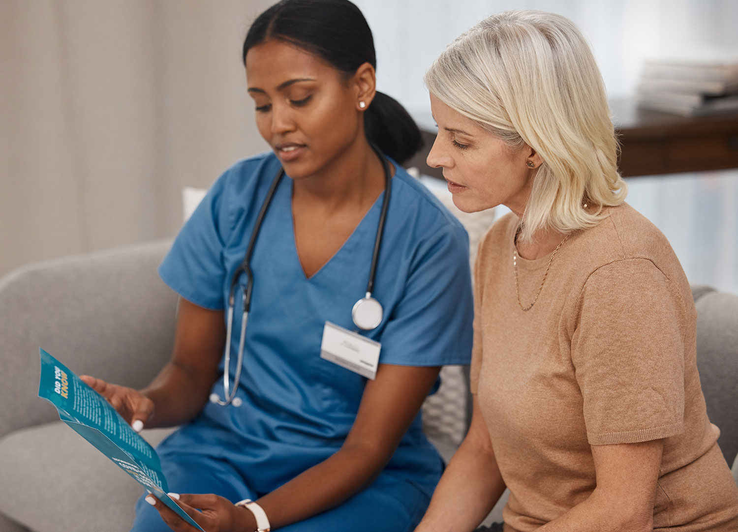 female doctor in scrubs talking to old woman patient