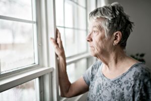 old white woman staring out window in a depressed way