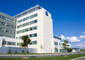 modern white hospital building underneath rich blue sky
